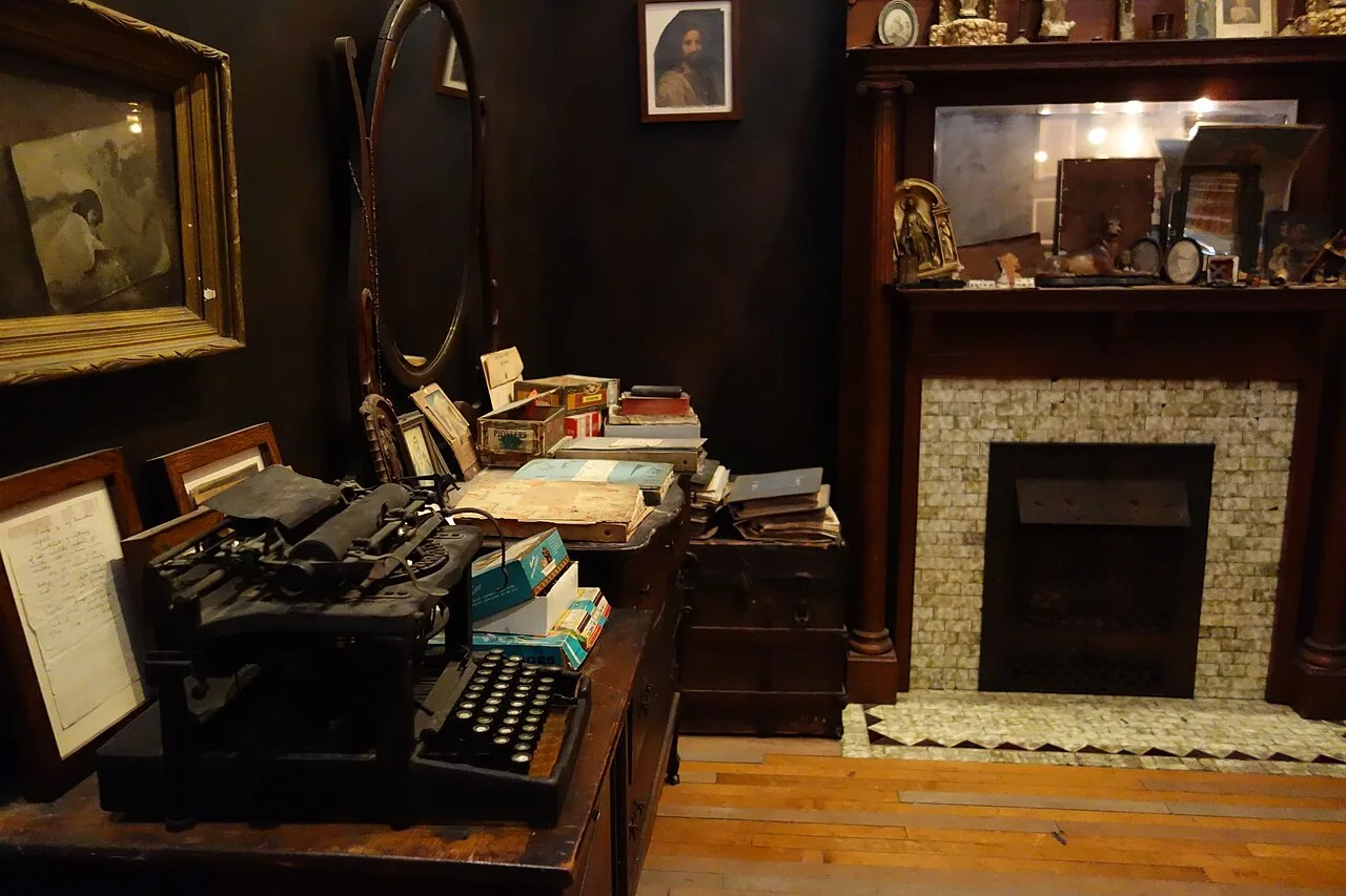 A small room with old furniture, paintings, and a typewriter