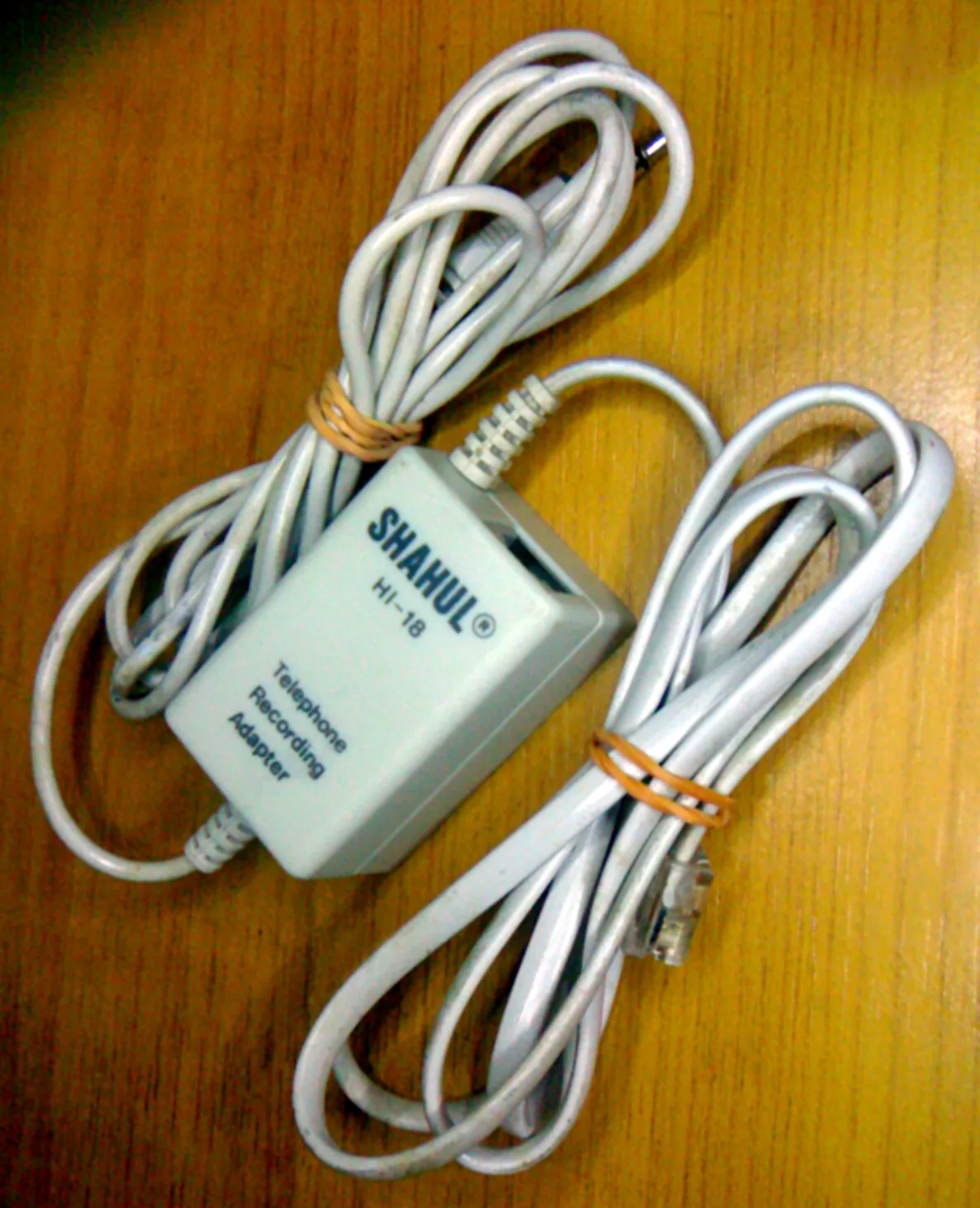 A telephone recording adapter (in-line tap). The phone jack connects to the wall socket while the phone being monitored